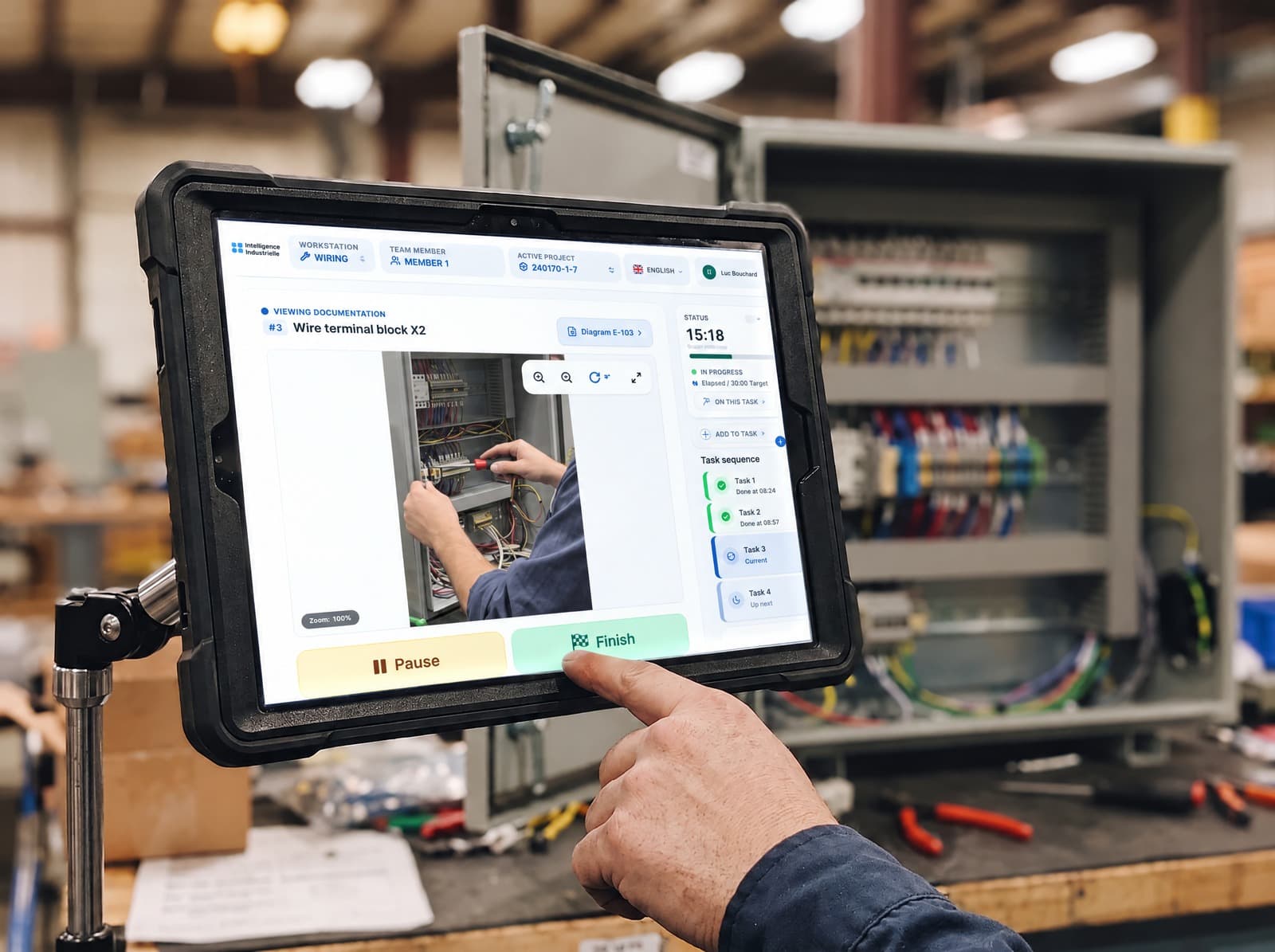 Operator completing a wiring task on the CLOCK tablet, in front of an electrical cabinet